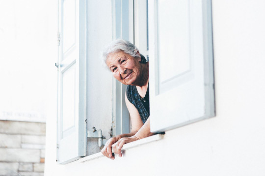 une personne âgée qui regarde par la fenêtre
