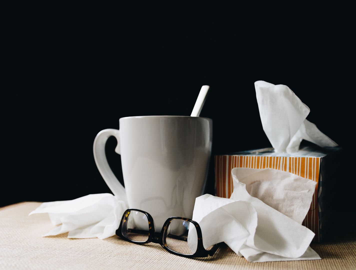 a cup, tissues and a pair of glasses